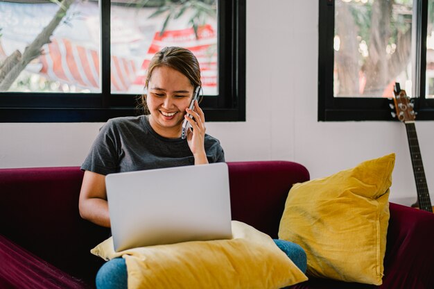 Mujer joven trabajando feliz desde casa con su portátil